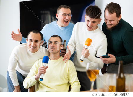Happy male friends having fun while singing karaoke at a bar. Having fun, celebrating. holiday, leisure, party concept 135696924