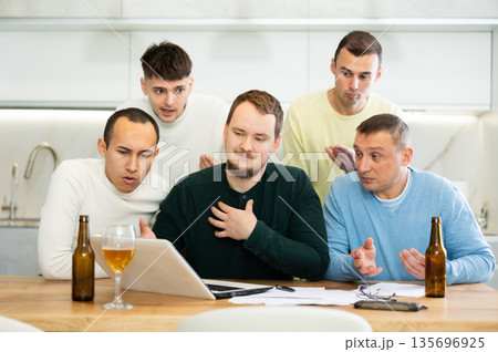 Group of male friends solving problems using laptop and drinking beer 135696925