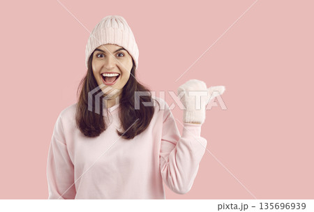 Joyful impressed young woman with happy facial expression pointing at empty space for advertisement Joyful impressed young woman with happy facial expression pointing at empty space for advertisement 135696939