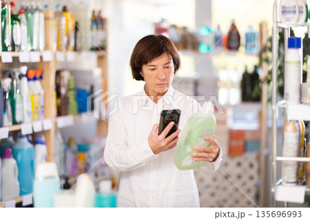 Elderly woman scanning qr code for detergent Elderly woman scanning qr code for detergent 135696993
