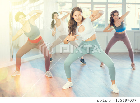 Young female teacher conducts modern hip hop dance lessons for group of girls 135697037