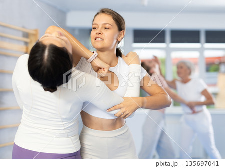 Woman practicing hand blocking with elbow strike to chin during sparring at self-defense training Woman practicing hand blocking with elbow strike to chin during sparring at self-defense training 135697041