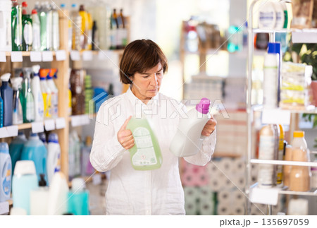 Elderly woman buyer chooses detergent in store Elderly woman buyer chooses detergent in store 135697059