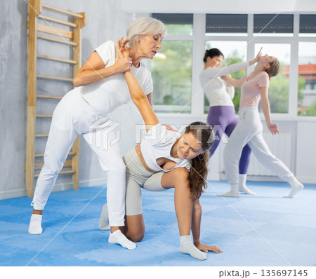 Mature woman applying arm lock technique in mock bout during self-defense class Mature woman applying arm lock technique in mock bout during self-defense class 135697145