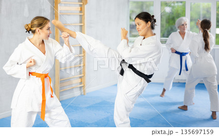 Asian woman in kimono working on kicks and blocks in training bout Asian woman in kimono working on kicks and blocks in training bout 135697159