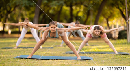 Yoga lesson visitors girls perform Himavanasana in park Yoga lesson visitors girls perform Himavanasana in park 135697211