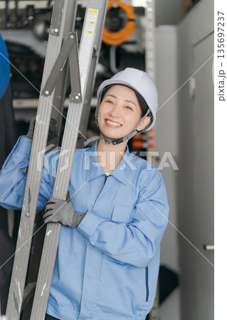 脚立を運ぶ女性作業員 脚立を運ぶ女性作業員 135697237