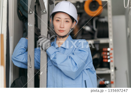 脚立を運ぶ女性作業員 脚立を運ぶ女性作業員 135697247