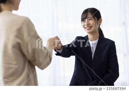 クライアントと笑顔で握手するスーツ姿の若い女性 135697394