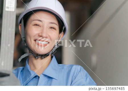 脚立を運ぶ笑顔の女性作業員 脚立を運ぶ笑顔の女性作業員 135697485