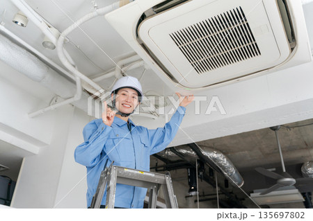 エアコンの点検をする女性作業員 135697802
