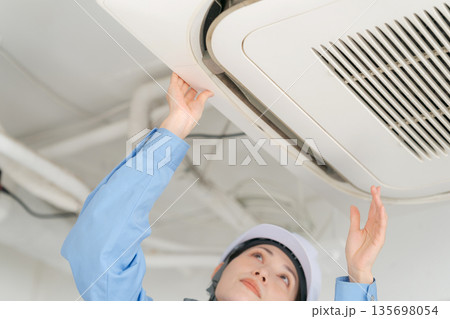 エアコンの点検をする女性作業員 エアコンの点検をする女性作業員 135698054