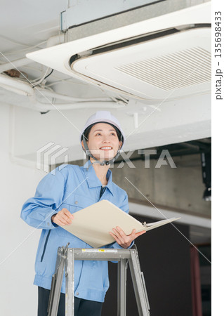 エアコンの点検をする女性作業員 エアコンの点検をする女性作業員 135698433