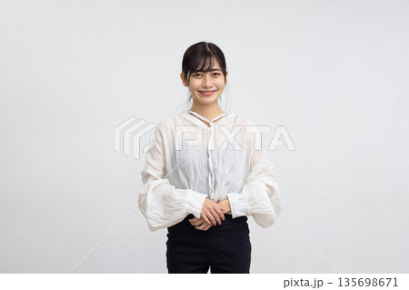 白い背景の前でカメラ目線で微笑む若い女性 135698671