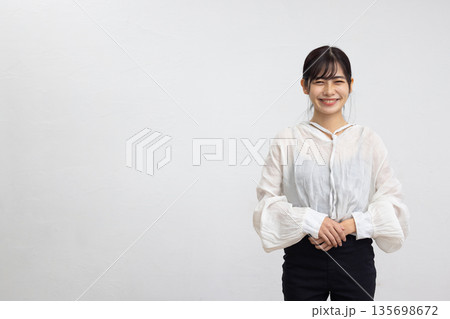 白い背景の前でカメラ目線で微笑む若い女性 135698672