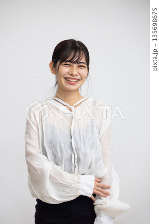 白い背景の前でカメラ目線で微笑む若い女性 白い背景の前でカメラ目線で微笑む若い女性 135698675