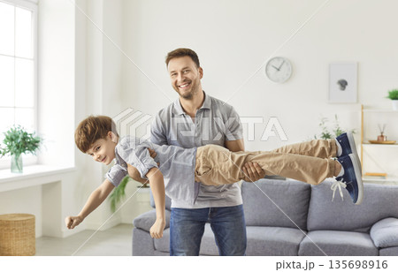 Happy father at home, enjoying to have fun play with cute excited little son, dad imitates plane fly 135698916