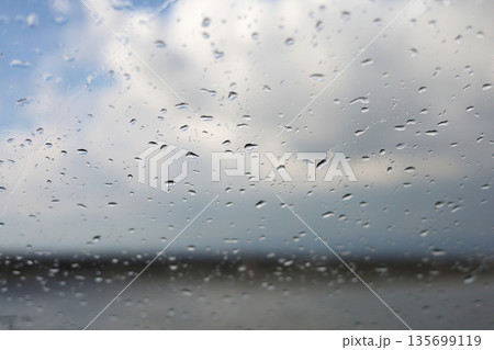 Raindrops on Window with Overcast Sky 135699119