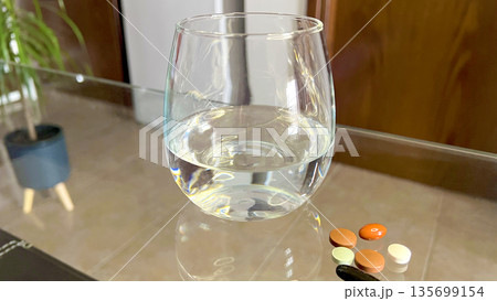 Pills and Glass of Water on Table Pills and Glass of Water on Table 135699154