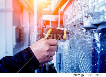Technician use infrared thermal imaging camera to check temperature at fuse-box Technician use infrared thermal imaging camera to check temperature at fuse-box 135699415
