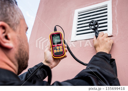 Technician use hand-held anemometer measuring air flowing measurement Technician use hand-held anemometer measuring air flowing measurement 135699418