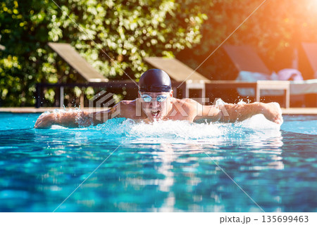 Young athletic man swimming in the swimming pool 135699463