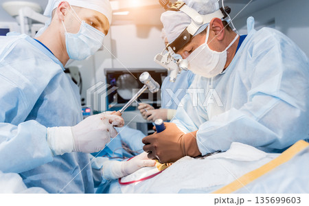 Spinal surgery. Group of surgeons in operating room with surgery equipment.  135699603