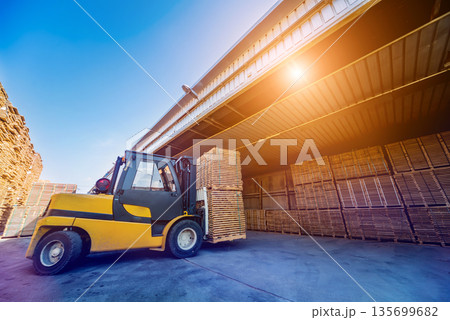Forklift loader load lumber into a dry kiln. Wood drying in containers. Forklift loader load lumber into a dry kiln. Wood drying in containers. 135699682