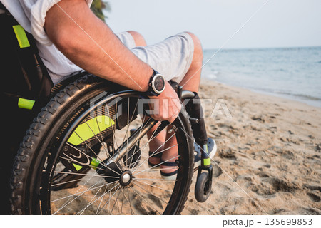 Disabled man in a wheelchair on the beach. 135699853