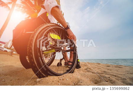 Disabled man in a wheelchair on the beach. Disabled man in a wheelchair on the beach. 135699862
