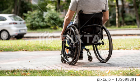 Handicapped man in wheelchair walk at the park alley 135699891