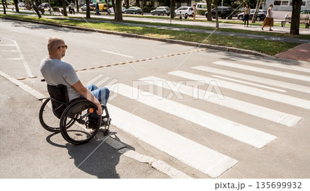 Handicapped man in wheelchair preparing to cross the road on pedestrian crossing 135699932