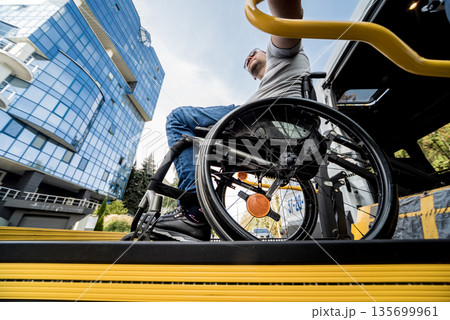 A man in a wheelchair on a lift of a vehicle for people with disabilities A man in a wheelchair on a lift of a vehicle for people with disabilities 135699961