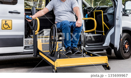 A man in a wheelchair on a lift of a vehicle for people with disabilities A man in a wheelchair on a lift of a vehicle for people with disabilities 135699967