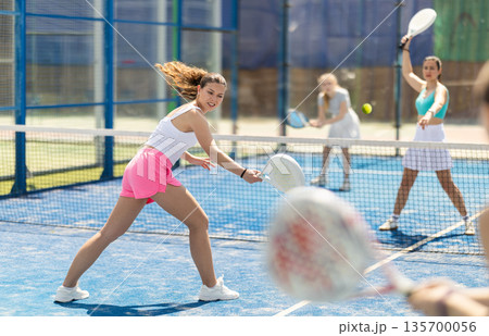Woman playing with other paddle tennis players 135700056