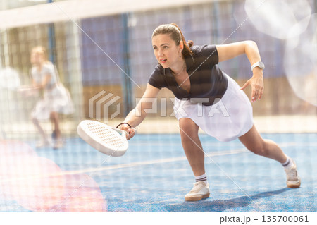 Adult woman playing doubles padel tennis 135700061