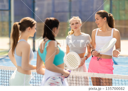 Female padel tennis players chatting on tennis court 135700082