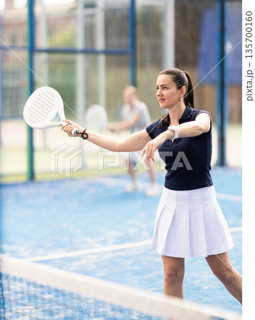 Adult woman playing doubles padel tennis 135700160