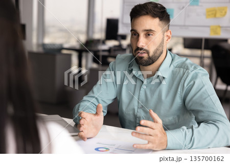 Professional man explains information presented in charts on table Professional man explains information presented in charts on table 135700162
