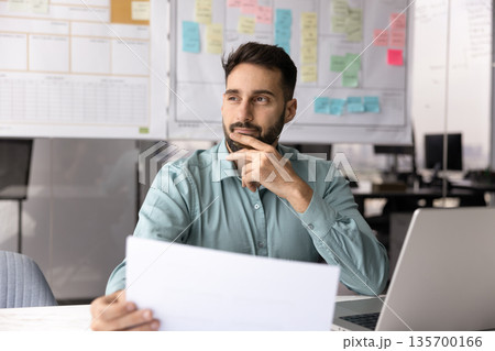 Man analyzing data and summarizing information with pensive expression 135700166