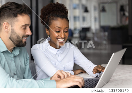 Two colleagues reviewing new AI program or platform in workplace 135700179