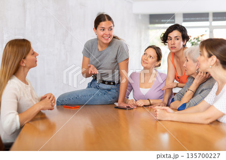 Smiling young girl discussing with female volunteer group Smiling young girl discussing with female volunteer group 135700227
