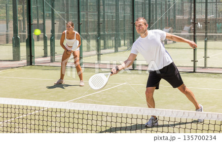 Sports woman and man playing padel on tennis court 135700234