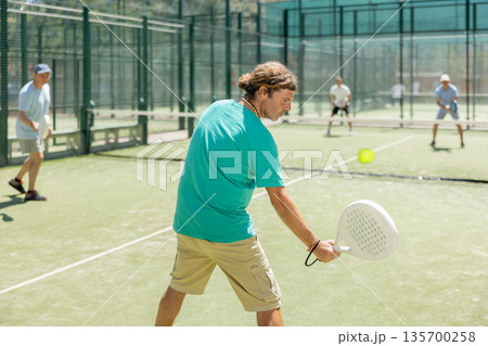 Adult men playing padel against two men 135700258
