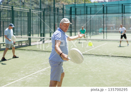 Adult and elderly men playing padel against two men Adult and elderly men playing padel against two men 135700295