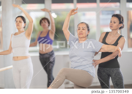 Ballet choreographer instructing senior woman in basic ballet techniques 135700349