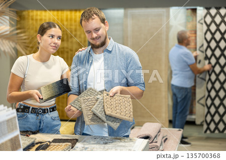 Married couple is interested in choosing softest and most beautiful carpet from carpet samples 135700368