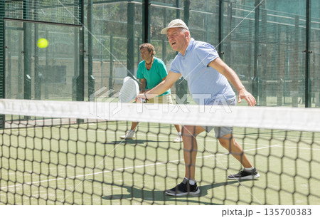 Elderly and adult men playing doubles padel 135700383