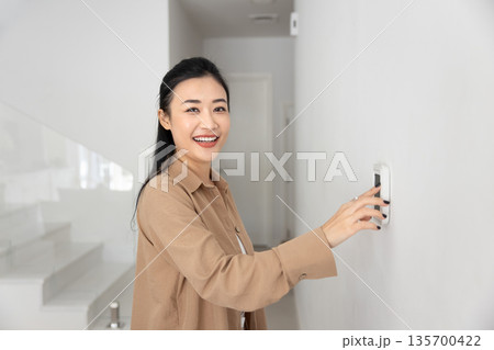 Portrait of Asian woman switching on alarm or climate control Portrait of Asian woman switching on alarm or climate control 135700422