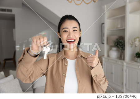 Woman showing to camera thumb-up gesture and bunch of keys 135700440